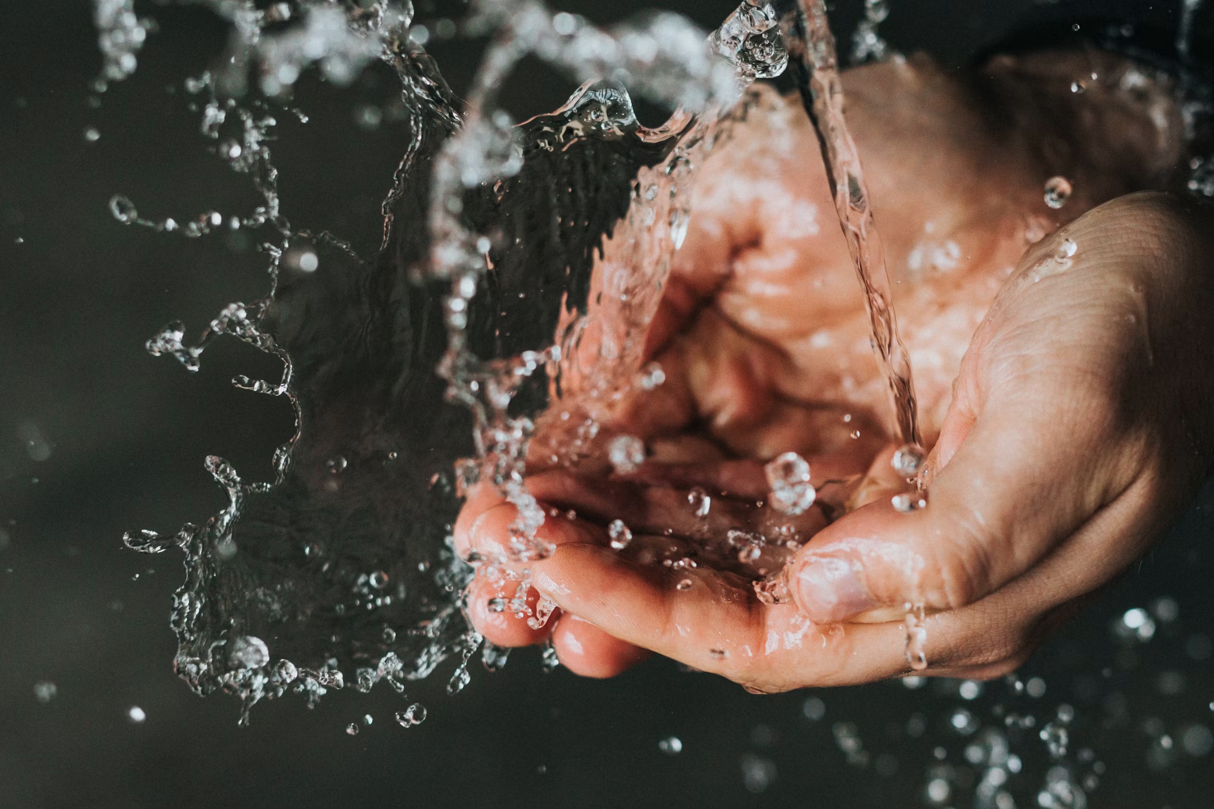 Hands catching running water, representing public access to clean water systems.